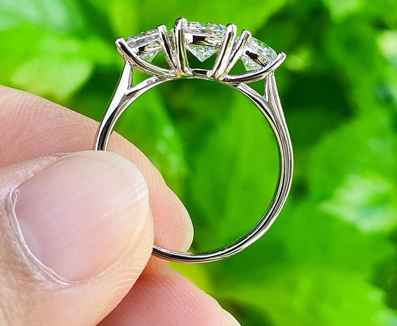 Bague en moissanite 1ct et 2x5mm en argent 925, trois pierres scintillantes tenue entre deux doigts