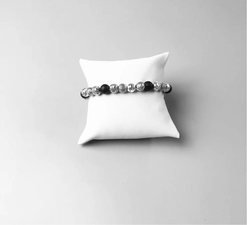 Bracelet perles noires et argent présenté sur coussin blanc – bijou élégant
