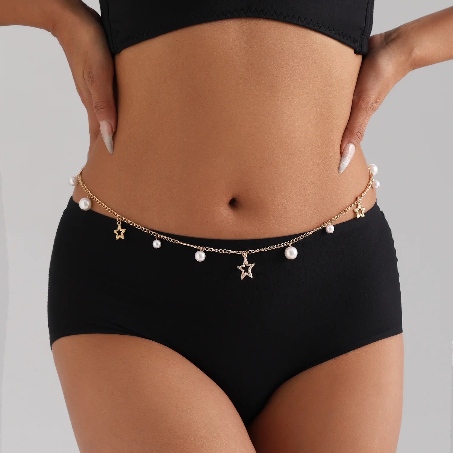 Femme en maillot noir mettant en valeur la chaîne coquillage