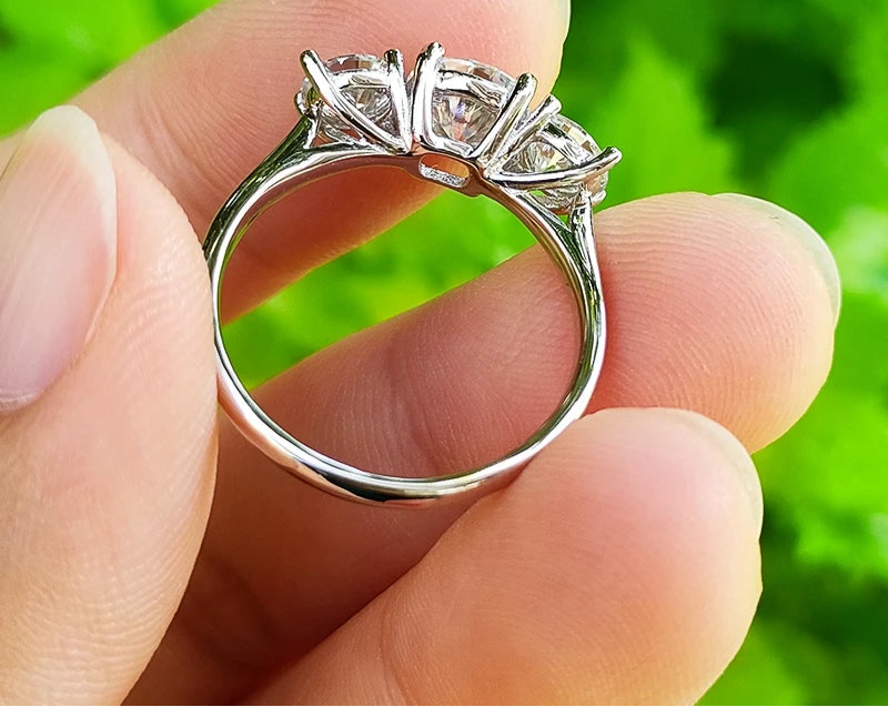 Bague en moissanite 1ct et 2x5mm en argent 925, trois pierres scintillantes tenue entre deux doigts