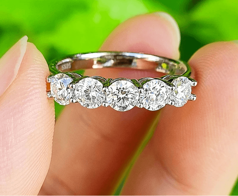 Bague en argent 925 avec cinq pierres brillantes, tenue entre les doigts