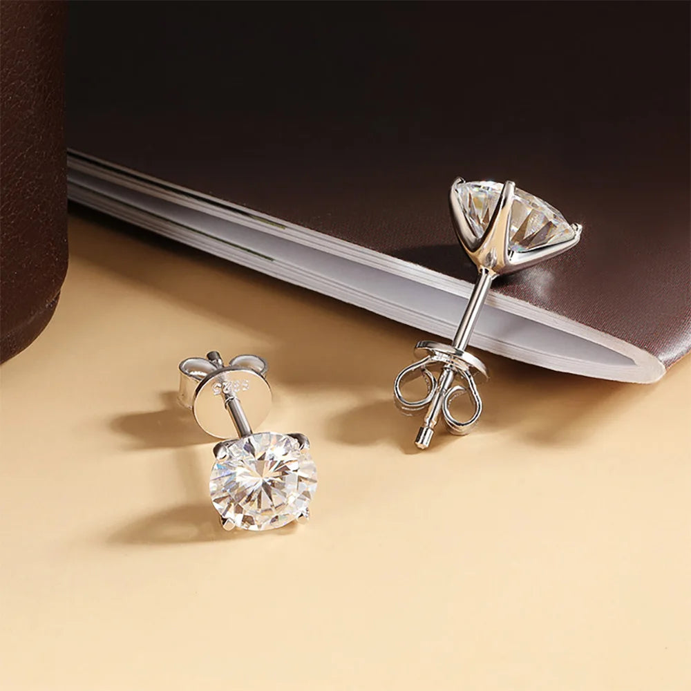 Boucles d’oreilles clou en zircon cubique serti argent, présentation sur fond sombre avec carnet